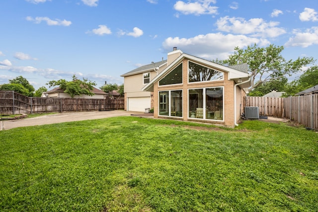 rear view of house featuring a garage, a yard, a chimney, brick siding, and concrete driveway