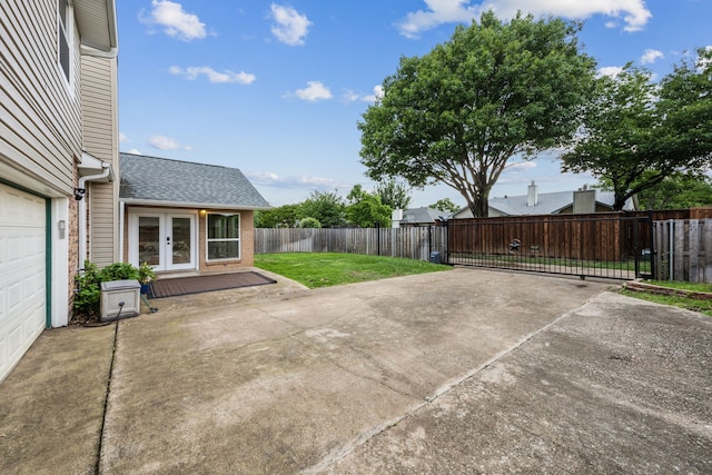 view of patio / terrace featuring a gate, fence, french doors, and driveway