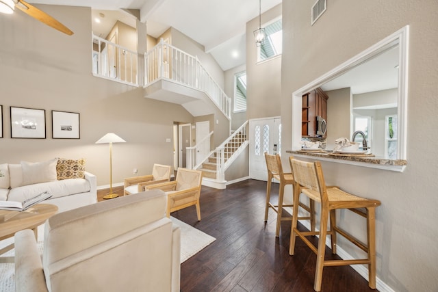 living area featuring visible vents, stairway, high vaulted ceiling, and a healthy amount of sunlight