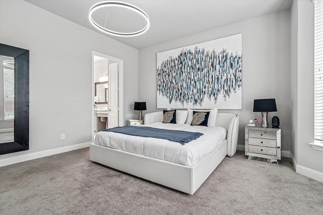bedroom with ensuite bathroom, baseboards, and carpet floors