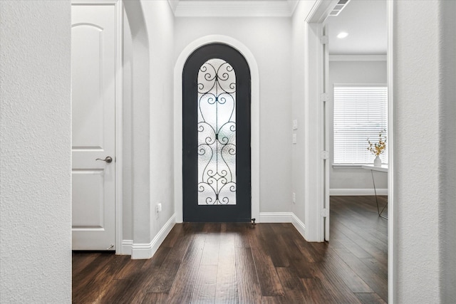 entryway with dark wood-type flooring, crown molding, baseboards, and arched walkways