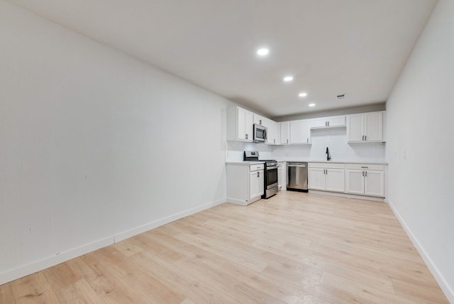 kitchen featuring a sink, appliances with stainless steel finishes, light wood-type flooring, recessed lighting, and backsplash