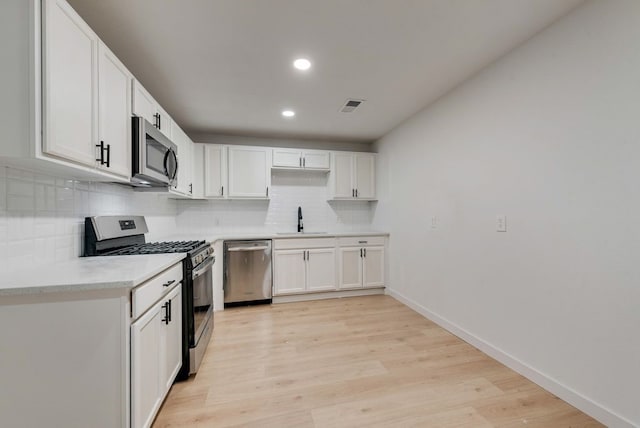 kitchen featuring a sink, tasteful backsplash, visible vents, light countertops, and appliances with stainless steel finishes