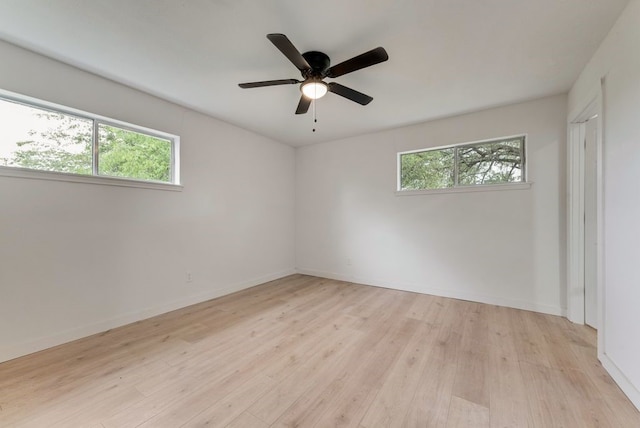 spare room featuring ceiling fan, light wood-type flooring, plenty of natural light, and baseboards