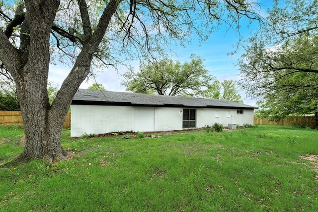 back of house featuring fence, a yard, and brick siding