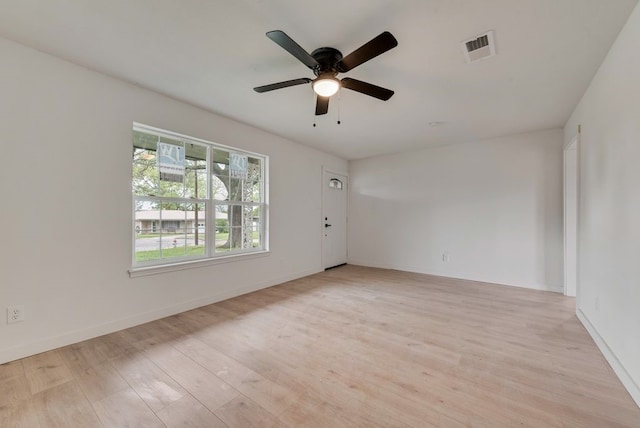 spare room featuring light wood finished floors, visible vents, ceiling fan, and baseboards
