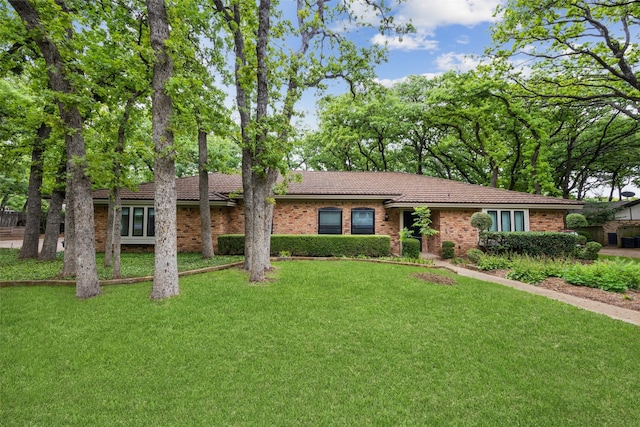 ranch-style house featuring brick siding, a tiled roof, and a front yard