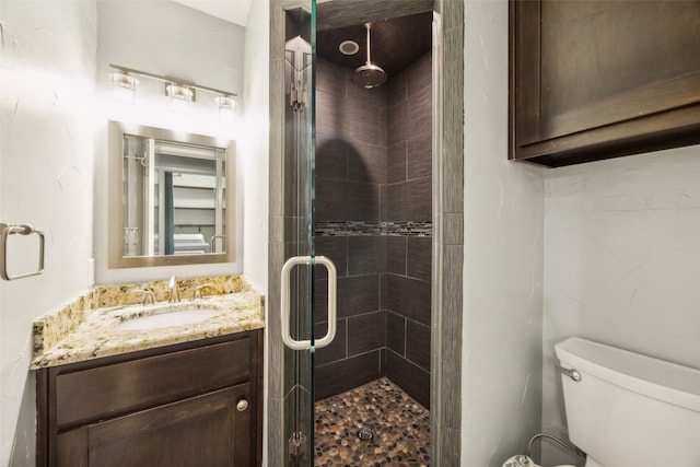 full bathroom featuring vanity, a stall shower, and toilet