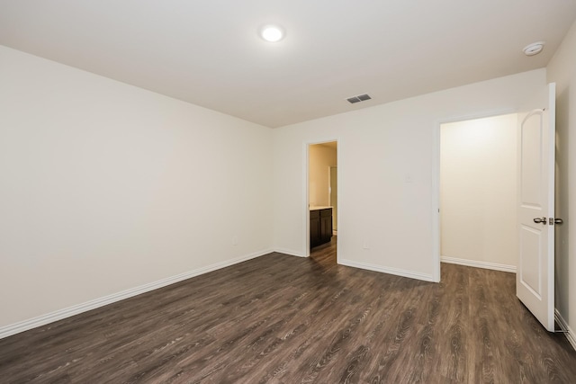 unfurnished bedroom with baseboards, visible vents, and dark wood-type flooring