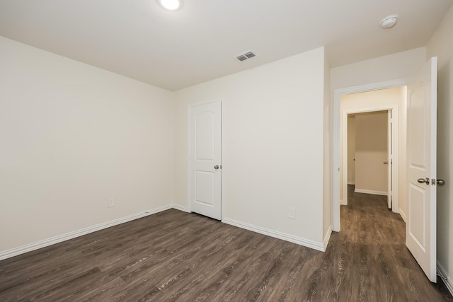 empty room with visible vents, baseboards, and dark wood-type flooring