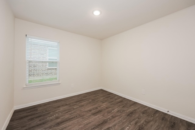 unfurnished room featuring dark wood-style flooring and baseboards