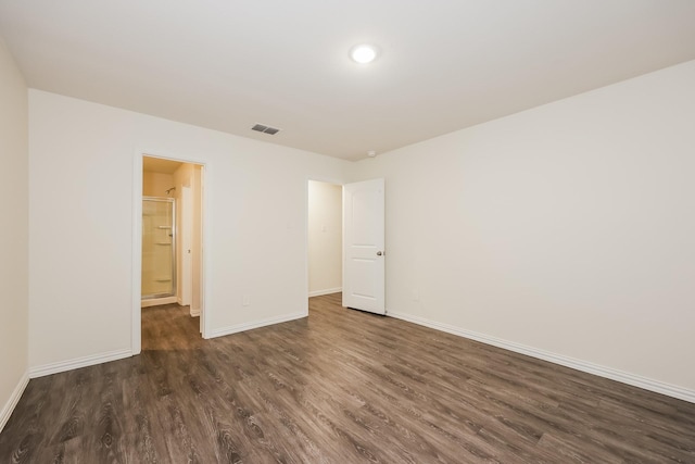 unfurnished room with visible vents, dark wood-style flooring, and baseboards
