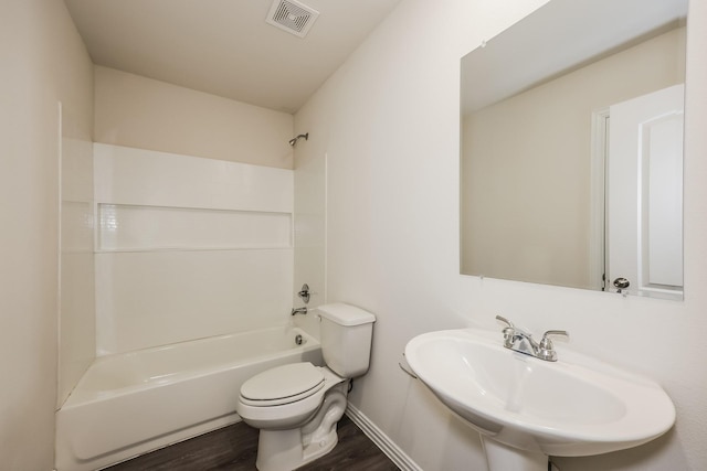 bathroom with wood finished floors, toilet, a sink, visible vents, and washtub / shower combination