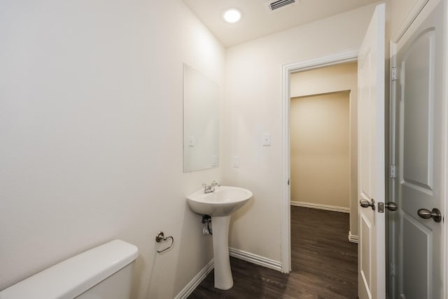bathroom featuring a sink, visible vents, baseboards, toilet, and wood finished floors