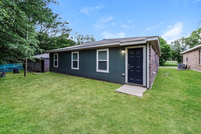 rear view of property featuring a yard and central air condition unit