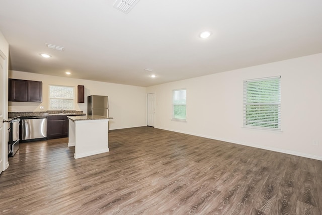 kitchen featuring appliances with stainless steel finishes, a sink, dark wood-style floors, a center island, and open floor plan