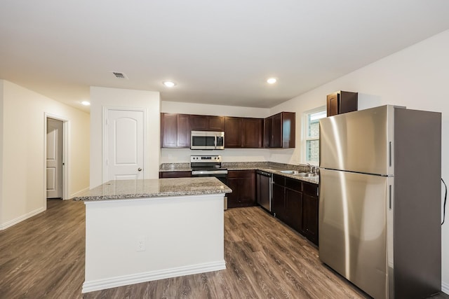 kitchen with a sink, appliances with stainless steel finishes, visible vents, dark brown cabinets, and dark wood finished floors