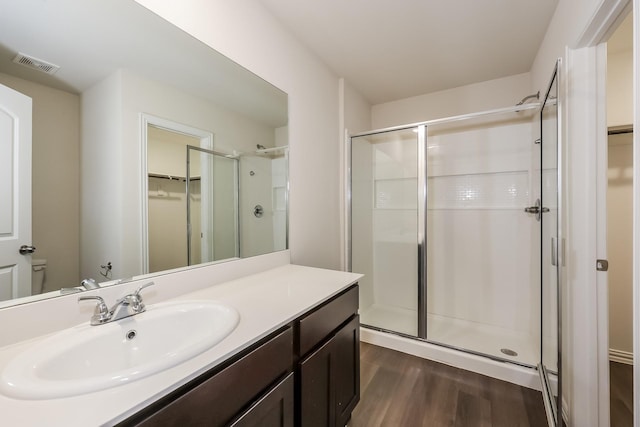 bathroom featuring visible vents, a stall shower, wood finished floors, and vanity