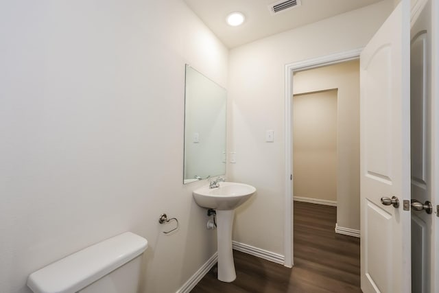 bathroom featuring a sink, toilet, visible vents, baseboards, and wood finished floors