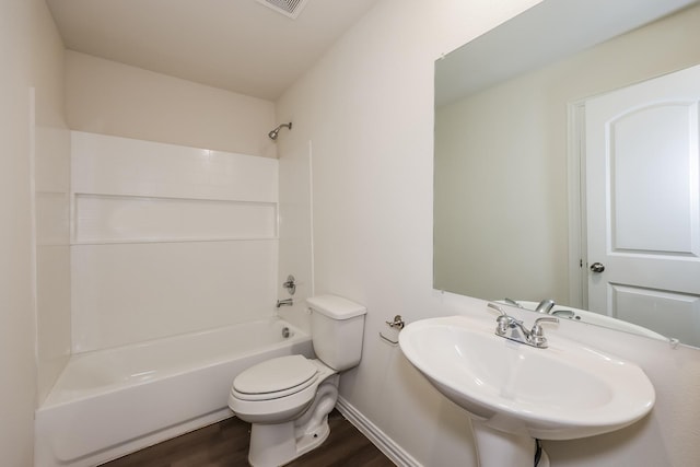 bathroom with a sink, baseboards, toilet, shower / bathing tub combination, and wood finished floors