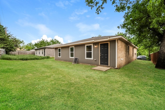 back of property with fence, a yard, and brick siding