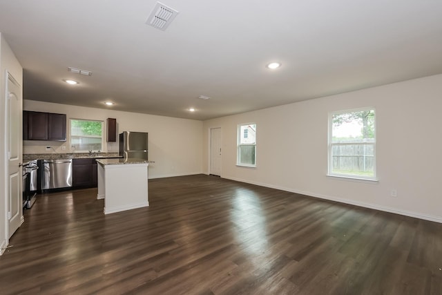 kitchen featuring stainless steel appliances, a center island, visible vents, open floor plan, and dark wood finished floors