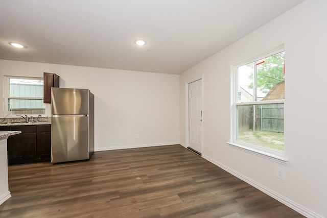 kitchen with dark wood-style flooring, baseboards, freestanding refrigerator, and dark brown cabinetry