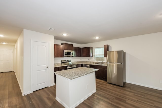 kitchen featuring a center island, stainless steel appliances, dark wood finished floors, and dark brown cabinetry