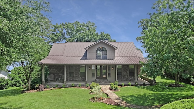farmhouse with covered porch, a front yard, metal roof, and stone siding