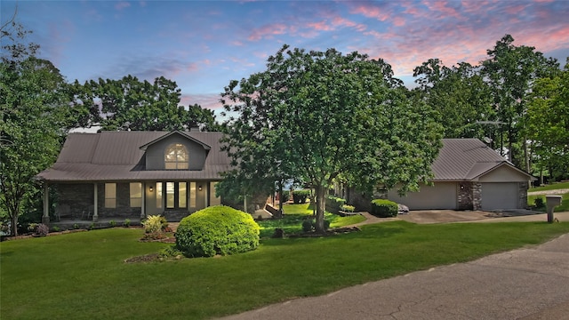 view of front facade with a garage, stone siding, a front yard, and concrete driveway