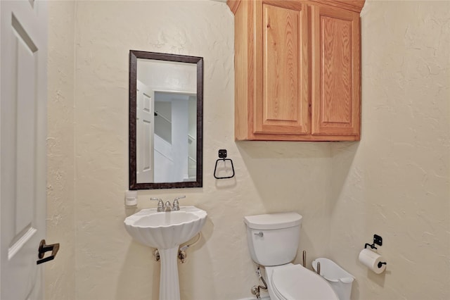 bathroom featuring a textured wall and toilet
