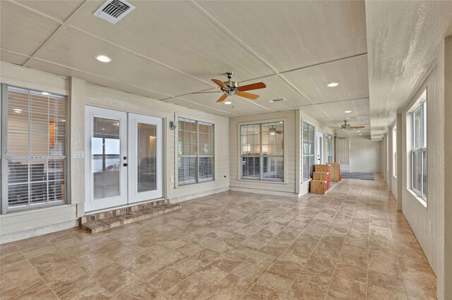 unfurnished sunroom featuring french doors, a ceiling fan, and visible vents
