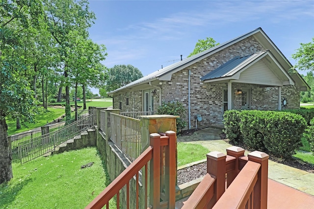 view of side of property with a lawn, brick siding, and fence