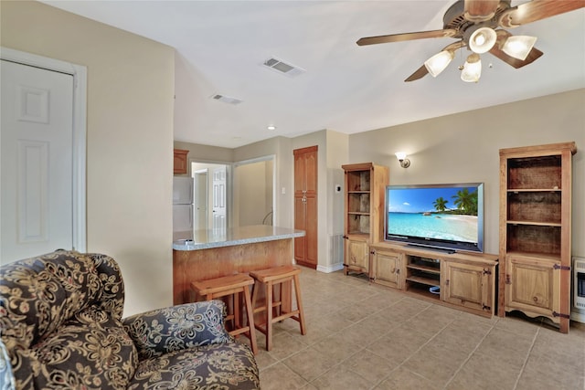 living room featuring ceiling fan, visible vents, light tile patterned floors, and heating unit