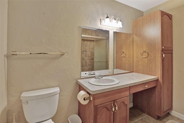 bathroom with vanity, a textured wall, toilet, tile patterned floors, and a tile shower