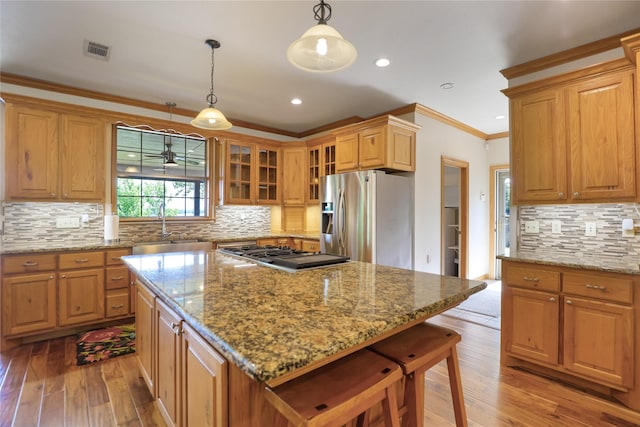 kitchen with visible vents, ornamental molding, a sink, light wood-style flooring, and appliances with stainless steel finishes