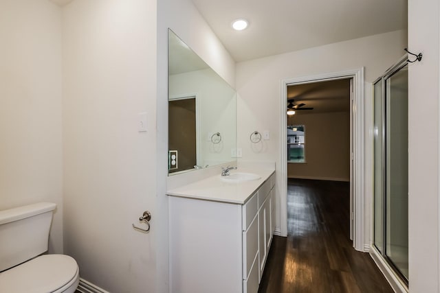 bathroom featuring vanity, a shower with shower door, wood finished floors, and toilet