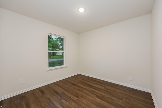 spare room featuring baseboards and dark wood-type flooring