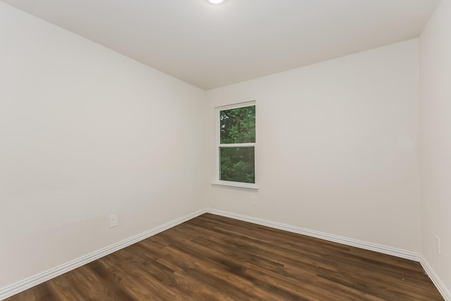 spare room featuring baseboards and dark wood finished floors
