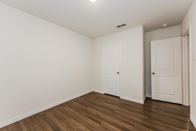 unfurnished bedroom featuring baseboards, visible vents, and dark wood-type flooring