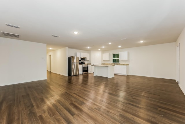 unfurnished living room featuring recessed lighting, dark wood-style floors, and visible vents