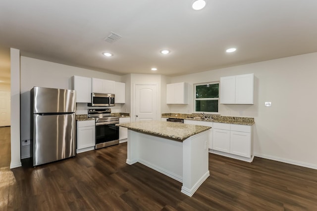kitchen featuring appliances with stainless steel finishes, dark wood finished floors, visible vents, and light stone counters