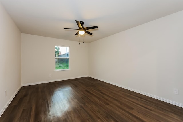spare room with a ceiling fan, baseboards, and dark wood finished floors