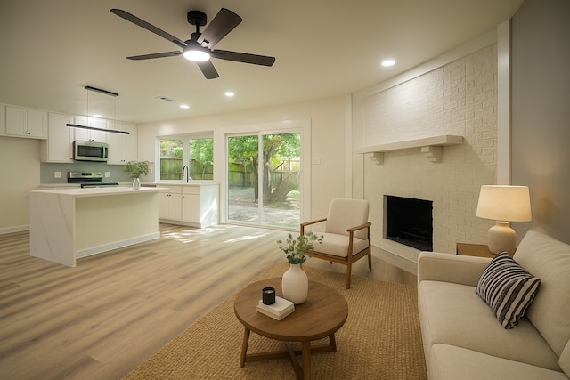 1830 Bosque Dr, Garland, TX 75040 - living area with light wood-style floors, a ceiling fan, a brick fireplace, and recessed lighting