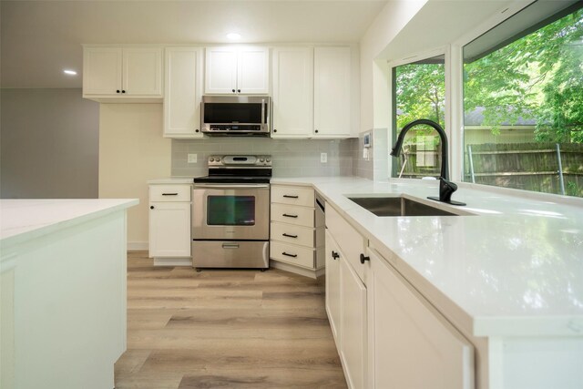 1830 Bosque Dr, Garland, TX 75040 - kitchen featuring stainless steel appliances, light wood-type flooring, recessed lighting, decorative backsplash, and white cabinets
