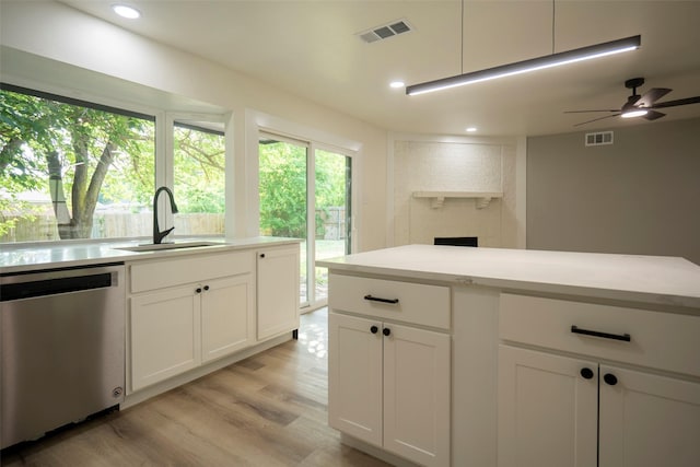 1830 Bosque Dr, Garland, TX 75040 - kitchen with stainless steel dishwasher, light wood-style flooring, white cabinetry, light countertops, and recessed lighting