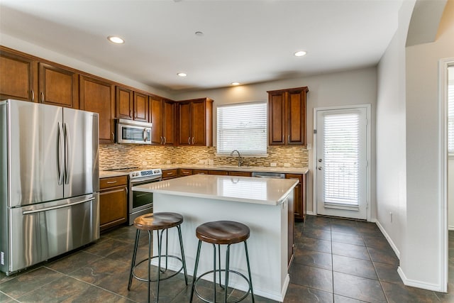 kitchen with appliances with stainless steel finishes, backsplash, a kitchen breakfast bar, and a sink