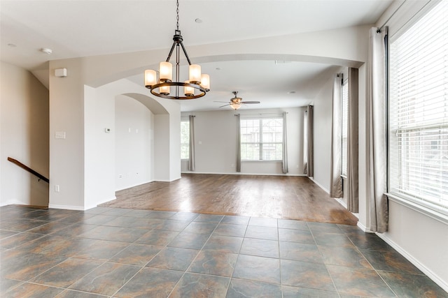 spare room featuring baseboards, arched walkways, and ceiling fan with notable chandelier