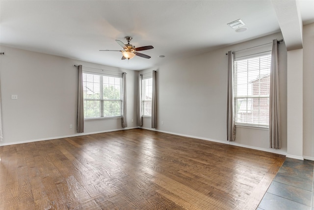 spare room featuring visible vents, ceiling fan, wood finished floors, and baseboards