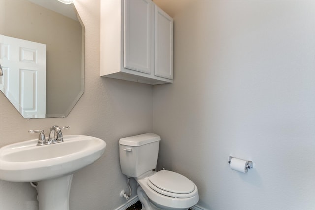 bathroom with baseboards, toilet, and a sink